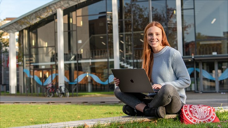 Studentin auf der Wiese vor dem Audimax
