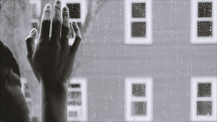 Schwarz-weiß Bild; Hand an Fensterscheibe gelegt