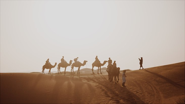 Menschen mit Kamelen in der Wüste