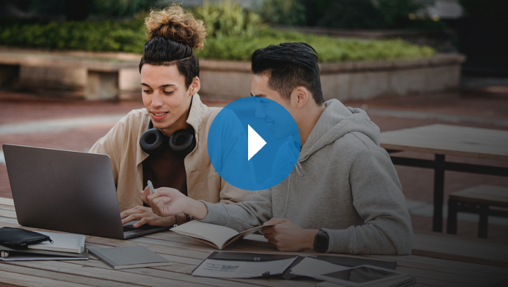 Zwei Studenten arbeiten draußen am Laptop
