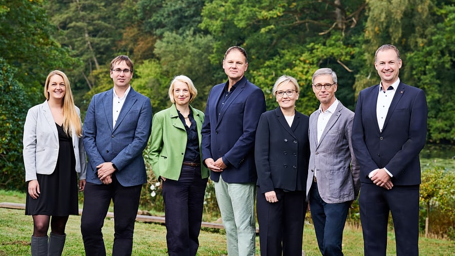 Das Präsidium der Universität Hamburg steht lächelnd auf einer Wiese