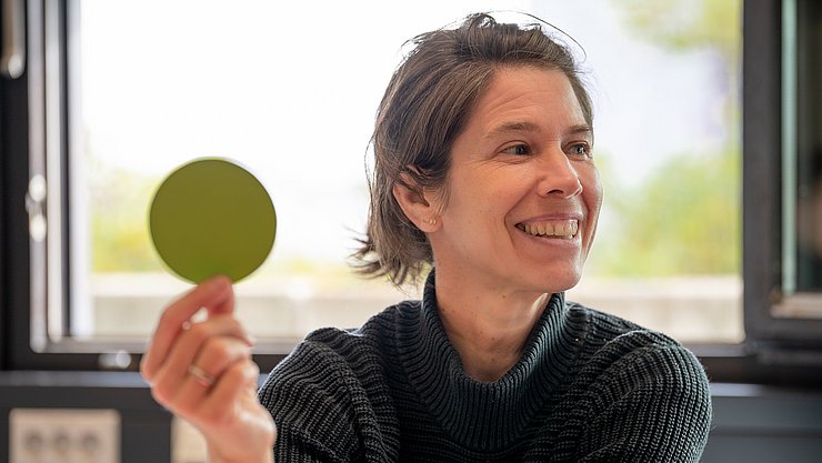 Eine Person hält einen grünen Punkt aus Papier in die Höhe.