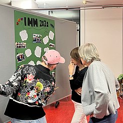 Studierende und Dozierende schauen sich ein Plakat an.