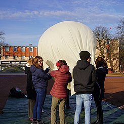 StudentInnen, die den Ballon mit Helium füllen.