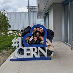 Gruppenbild vorm Eingang des Cern. Die Exkursionsteilnehmenden stehen hinter dem Cern-Logo.