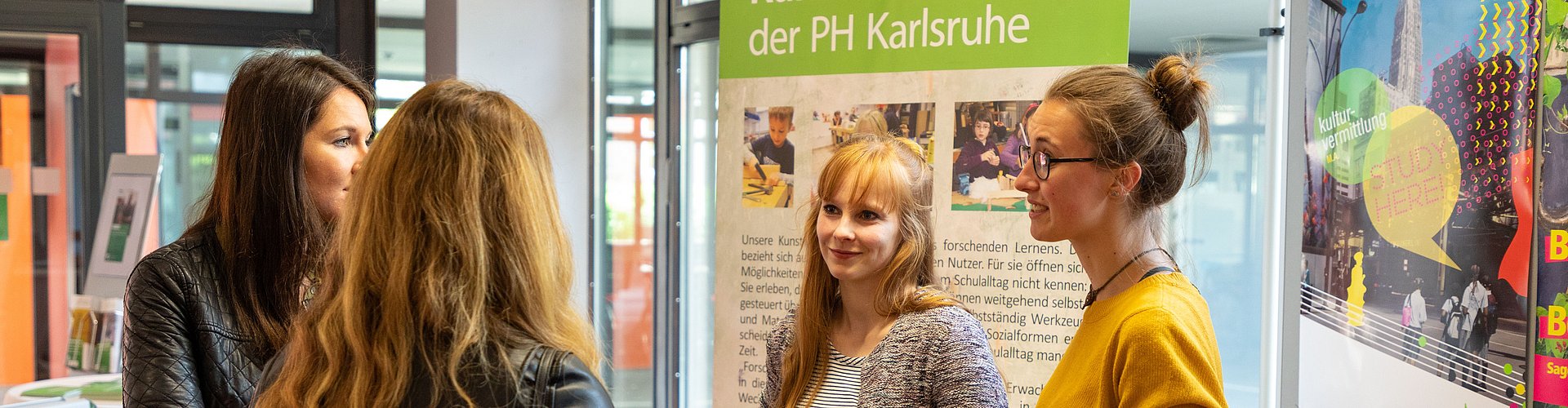 Zwei Studierende präsentieren an einem Infostand ihr Studienfach.