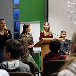 Auf dem Bild ist eine Vortragssituation zu sehen.